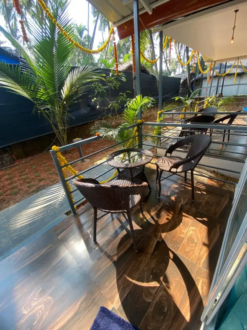 Outdoor seating area at Saffron Sun Palolem with palm trees and a shaded terrace