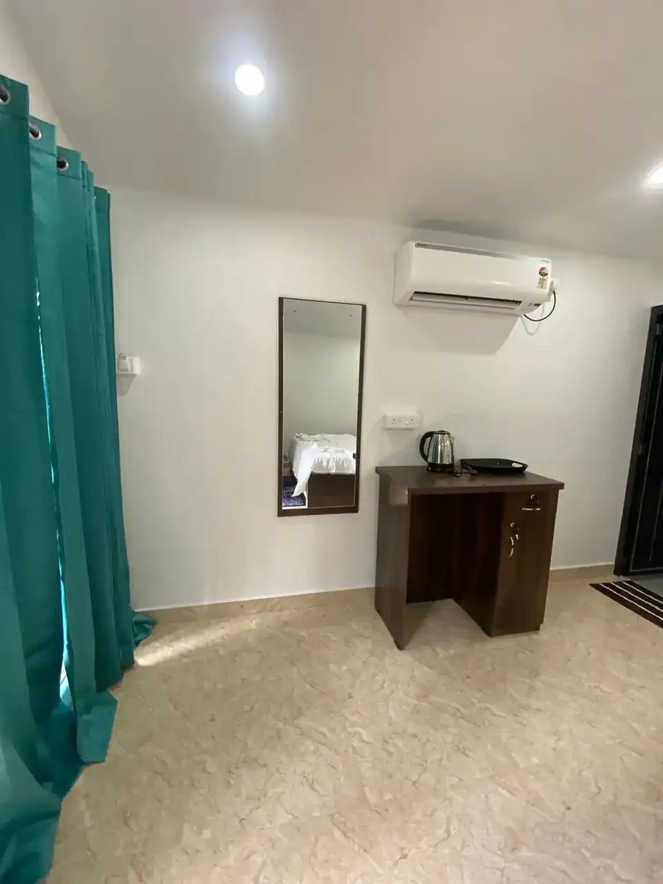 Guest room interior at Saffron Sun Palolem with desk, mirror and air conditioner